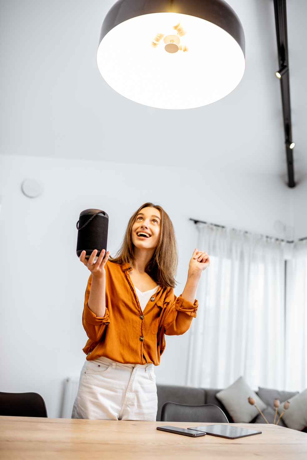 Woman controlling light with a smart speaker at home