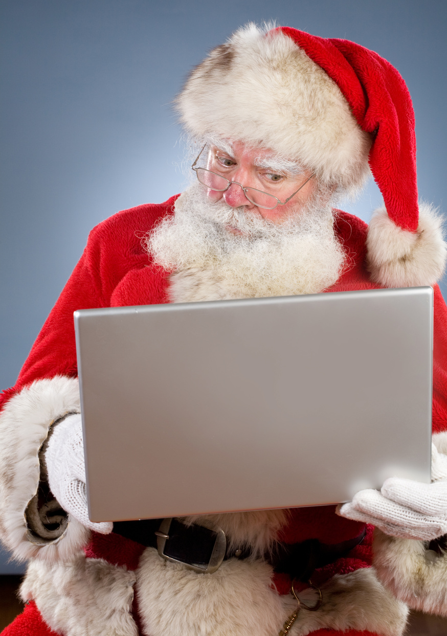a person dressed as Santa Claus is using a laptop computer and seems curious as to what he can achieve with it.