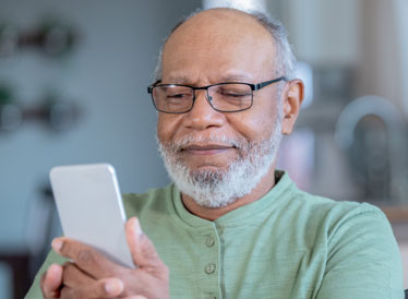 an individual with a beard and glasses using a cell phone and appears to be very pleased to be using it with ease.